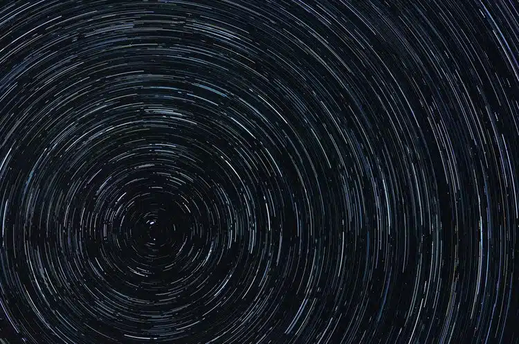 Star trail notturno con scie circolari delle stelle concentriche su cielo notturno scuro