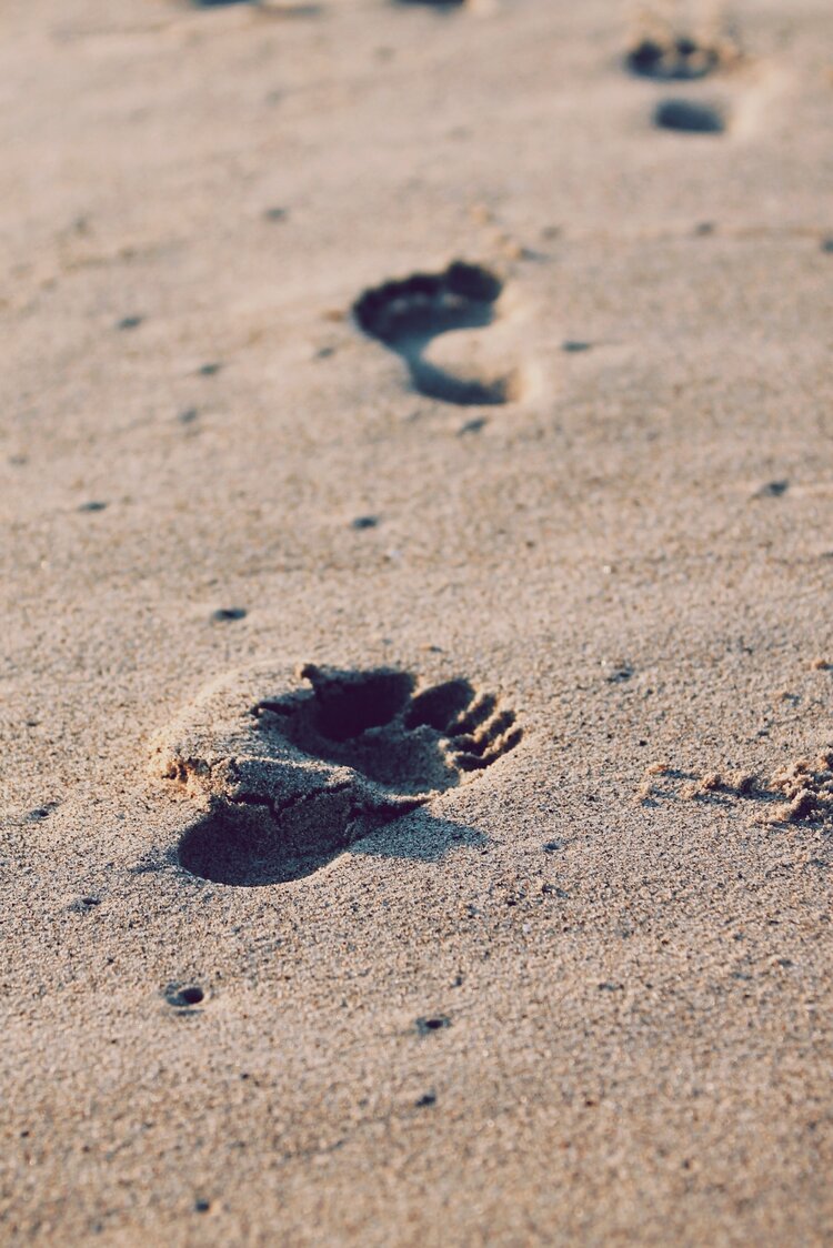 Impronte di Piedi Scalzi nella Sabbia Primo piano di piedi scalzi che lasciano impronte nella sabbia dorata, inquadratura verticale