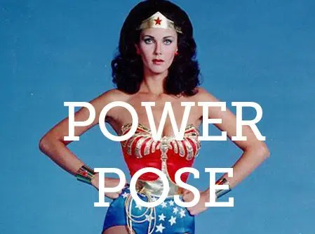 Costume ispirato a Wonder Woman su sfondo blu con testo POWER POSE e posa a mani sui fianchi