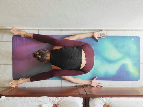 Upavistha Konasana – Vista Aerea su Tappetino Iridescente Vista dall'alto di una persona in Upavistha Konasana su un tappetino yoga multicolore con riflessi iridescenti