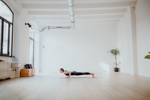 Chaturangadandasana – La Postura a Quattro Arti in Studio Persona in chaturanga dandasana su tappetino, in uno studio luminoso con pareti bianche e pavimento in legno