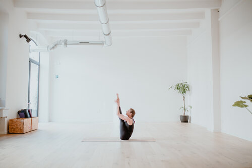 Persona in navasana (posizione della barca): busto e gambe sollevati in equilibrio in uno studio yoga