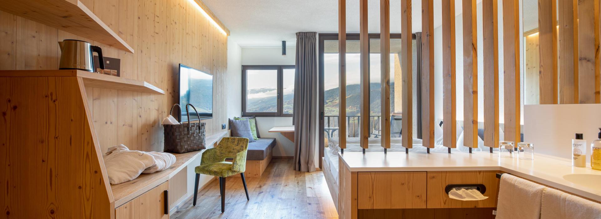 bright-hotel-room-with-wooden-furniture-modern-sink-area-cozy-sitting-corner-and-mountain-view